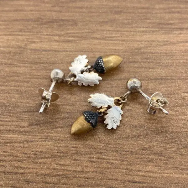 Silver and gold acorn earrings with leaves.