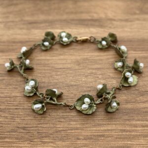 A bracelet with green leaves and pearls.
