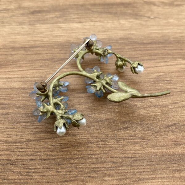 Gold floral brooch with blue flowers and pearls.