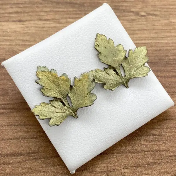 Gold leaf earrings on white background.