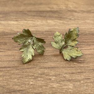 Gold leaf earrings on wooden background.