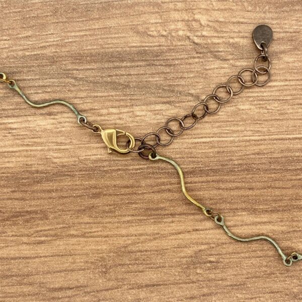 Gold and bronze necklace clasp on wood.