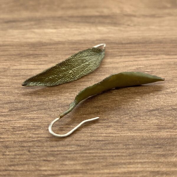 Gold leaf shaped earrings on wood.