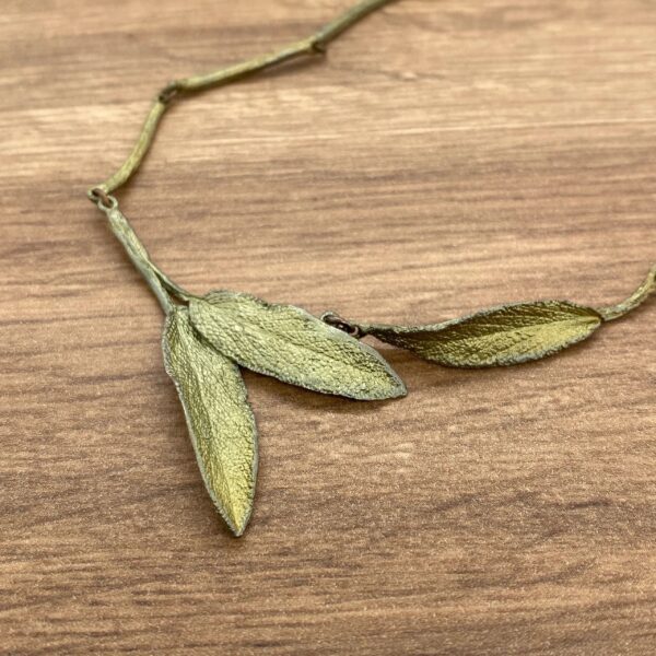 Gold leaf necklace on wooden surface.