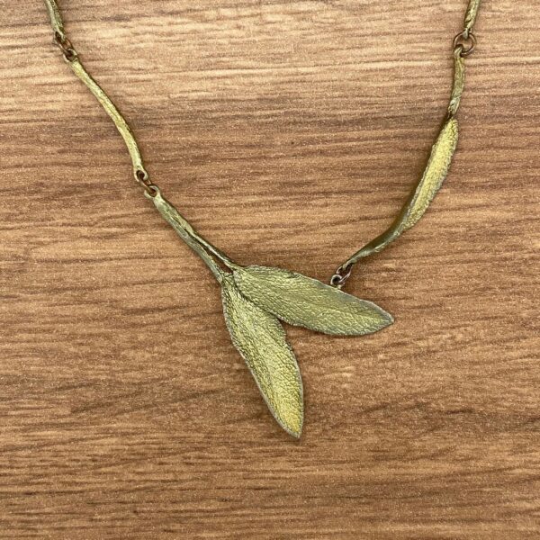 Gold leaf pendant necklace on wood.