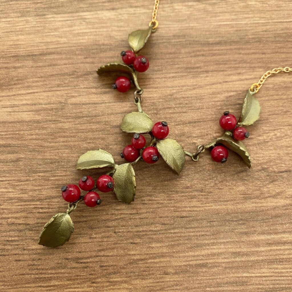 Gold necklace with red berry sprigs.