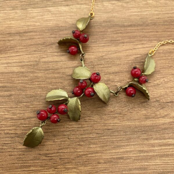 Gold necklace with red berry sprigs.