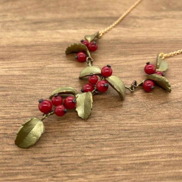 Gold necklace with red berries and leaves.