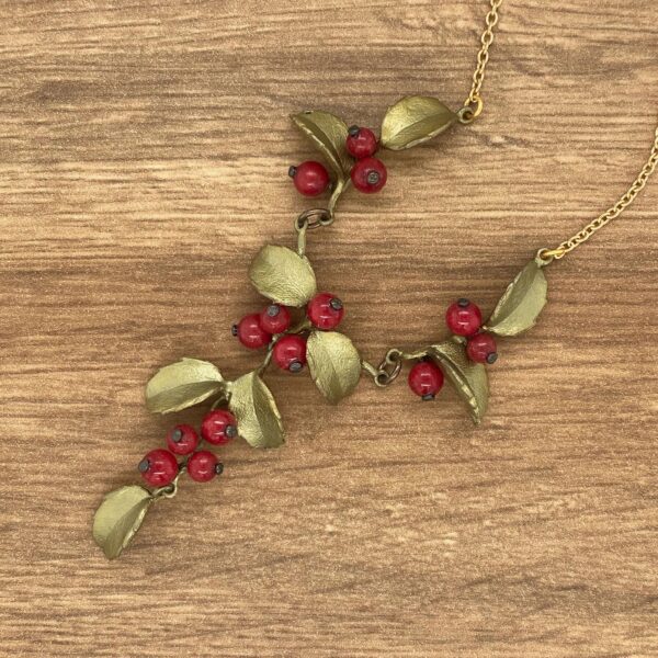 Gold necklace with red berries and leaves.