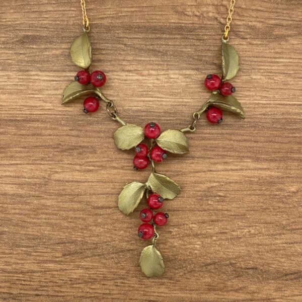 Gold necklace with red berry clusters.