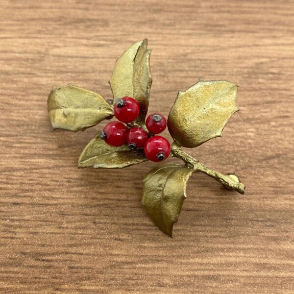 Gold holly sprig with red berries.