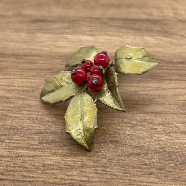 Gold holly leaf brooch with red berries.