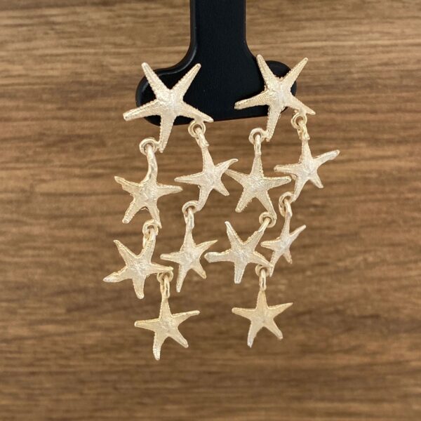 Gold starfish dangle earrings on display.