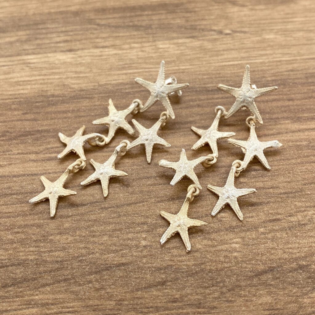 Gold starfish dangle earrings on wood.