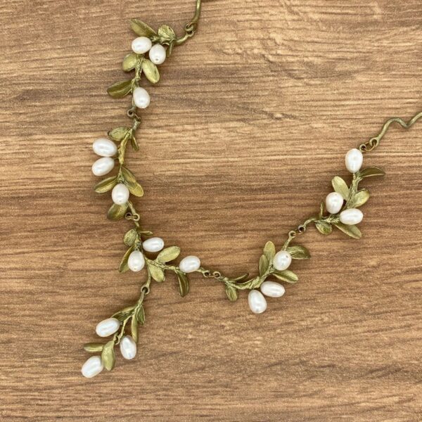 Gold leaf and pearl necklace on wood.