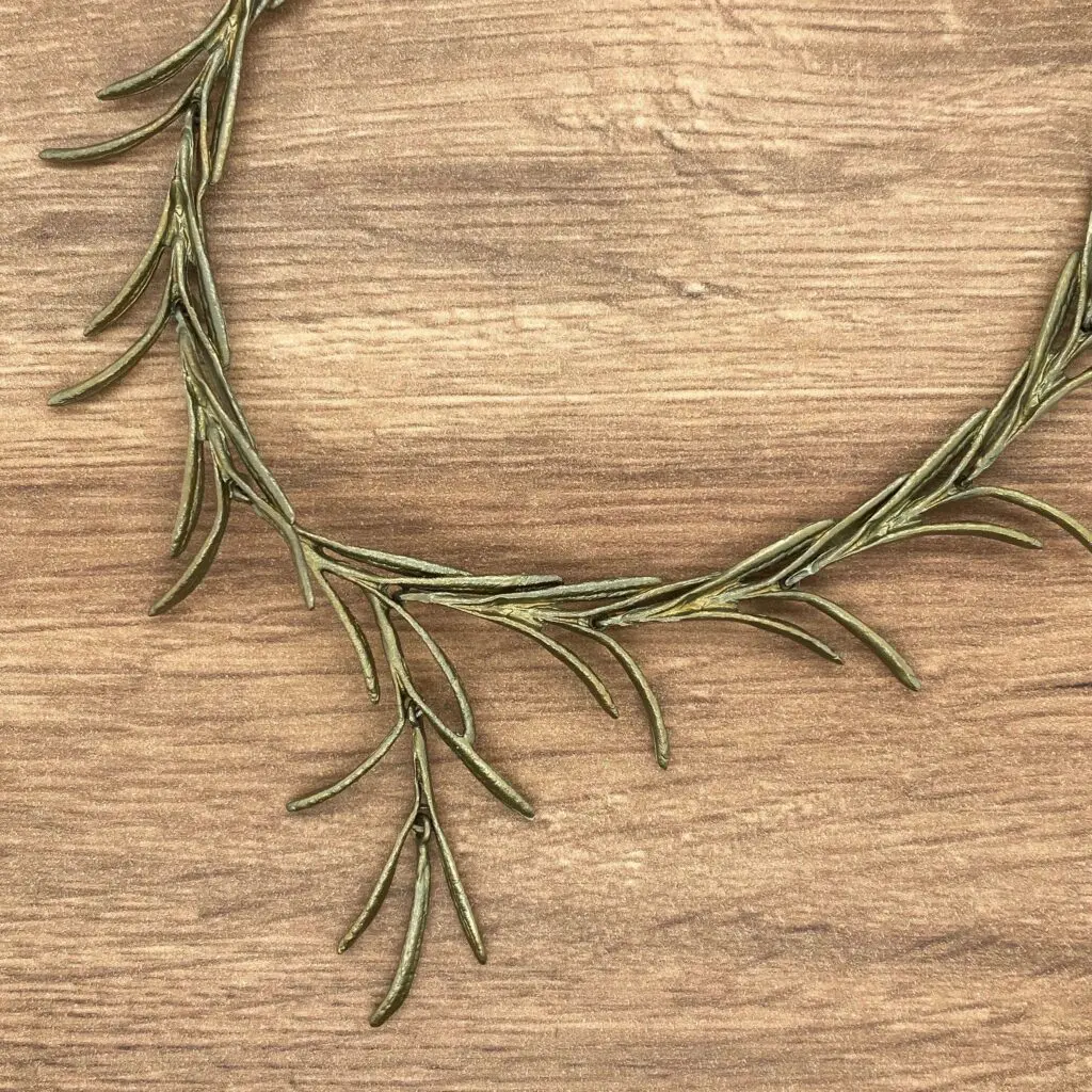 Gold rosemary branch necklace on wood.