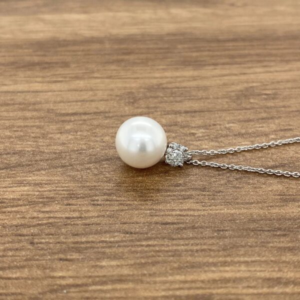 Pearl and diamond pendant necklace on wood.