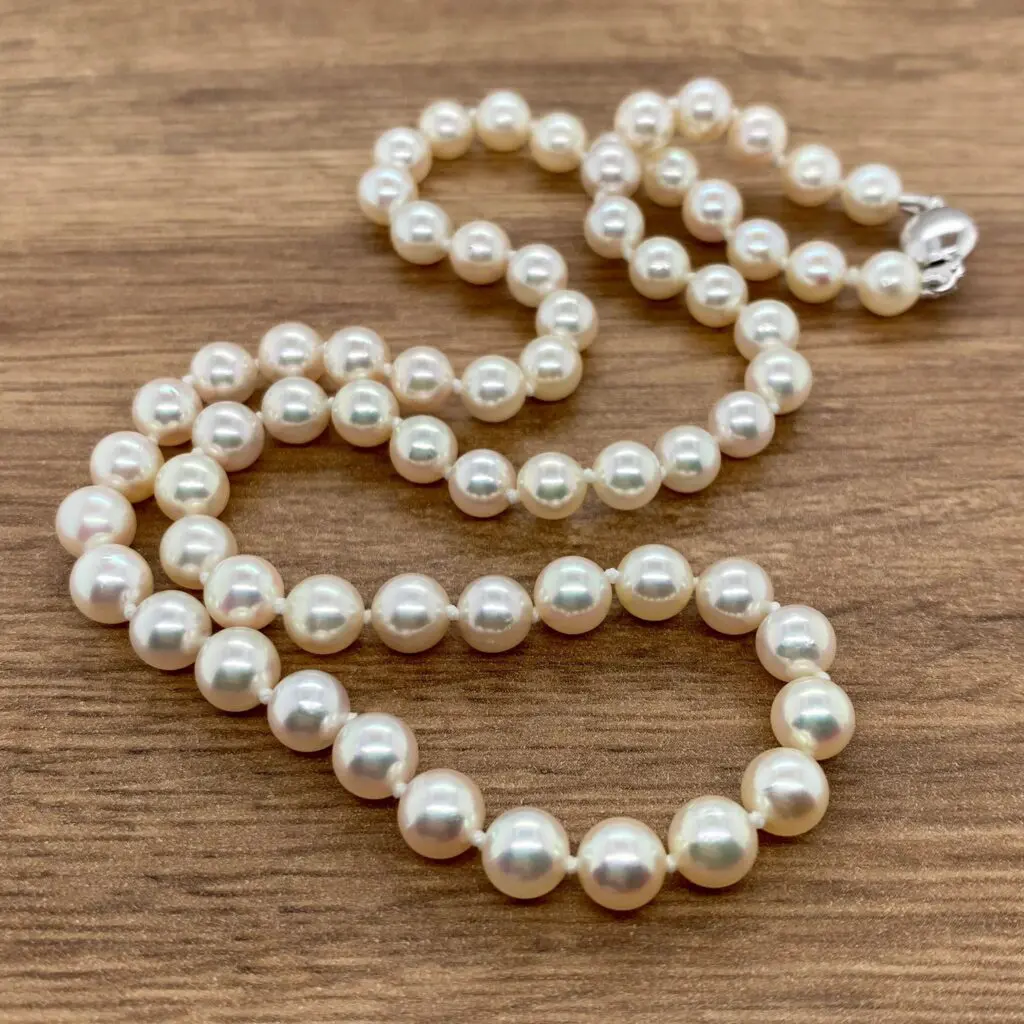 White pearl necklace on wooden surface.