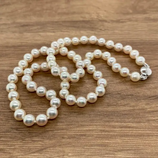 White pearl necklace on wooden surface.