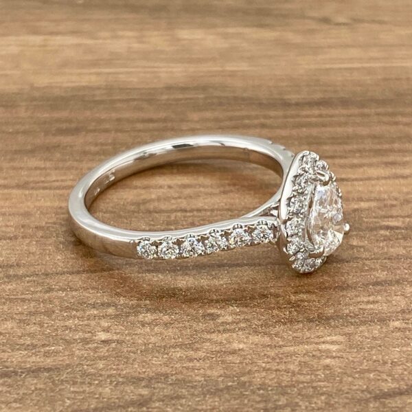 Diamond pear-shaped engagement ring on wood.