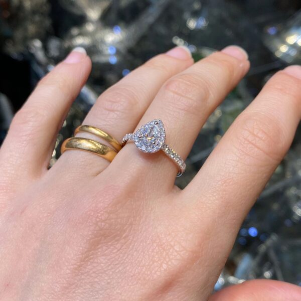 Hand wearing pear-shaped diamond ring.