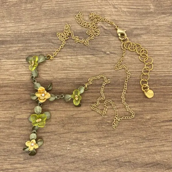 Gold chain necklace with green flower accents.