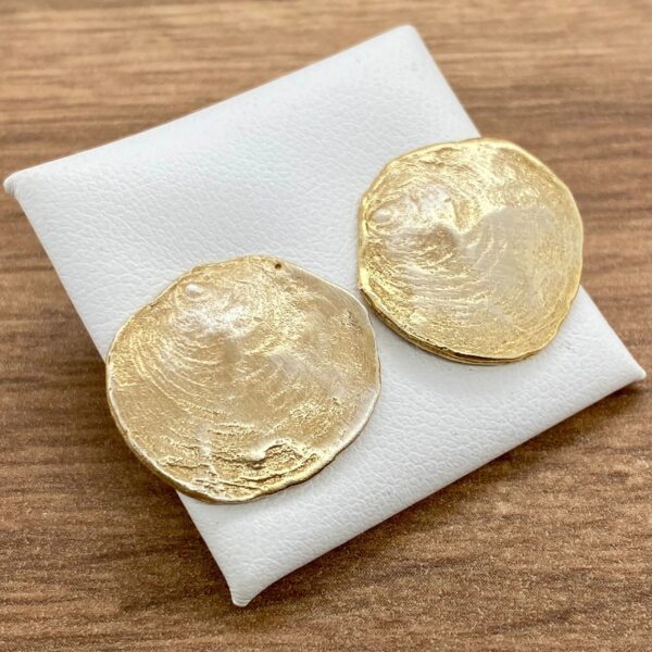 Gold textured round earrings on white.