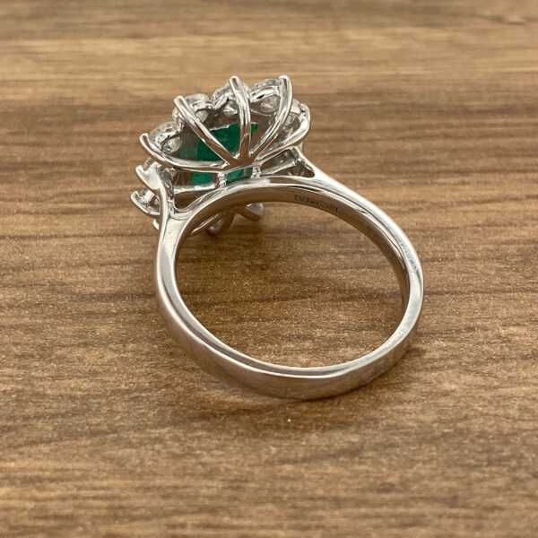 Emerald and diamond ring on wood background.