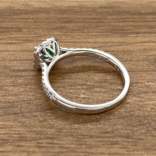 Emerald and diamond engagement ring on wood.