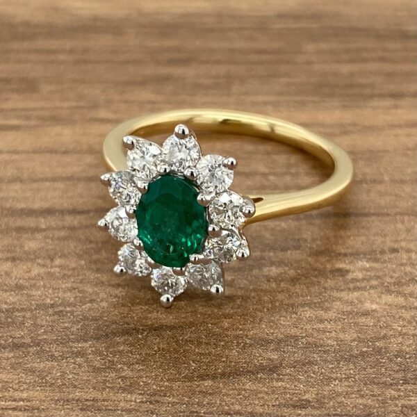 Gold ring with emerald and diamond halo.