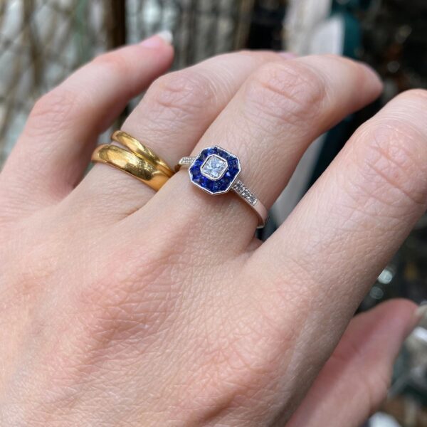 Hand wearing a sapphire and diamond ring.