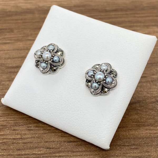 A pair of silver stud earrings with blue pearls.