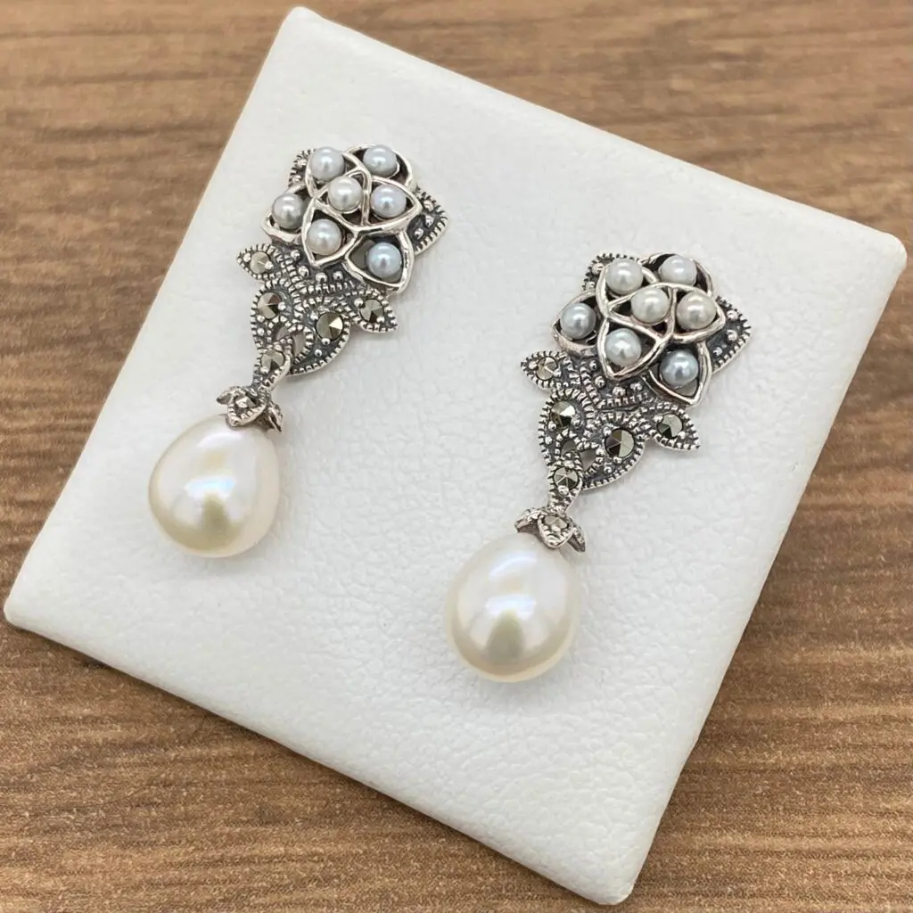 A pair of earrings with pearls and diamonds.