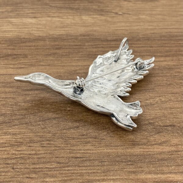 Sterling silver goose brooch with wings spread.