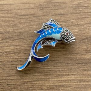 An Aquamarine & Diamond Large Oval Cluster Earrings brooch on a wooden table.