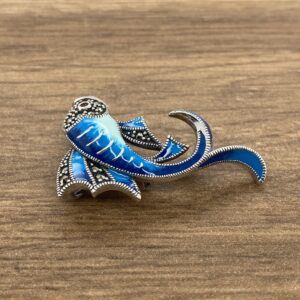 An Aquamarine & Diamond Large Oval Cluster Earrings brooch on a wooden table.