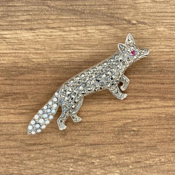 Jeweled fox brooch on wood background.