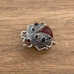 A red and black ladybug brooch on a wooden table.