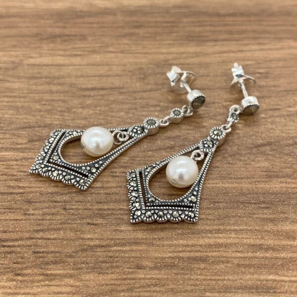 Silver dangle earrings with pearl accents.