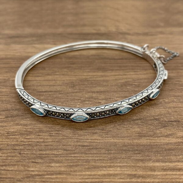 A silver bangle bracelet with turquoise stones.