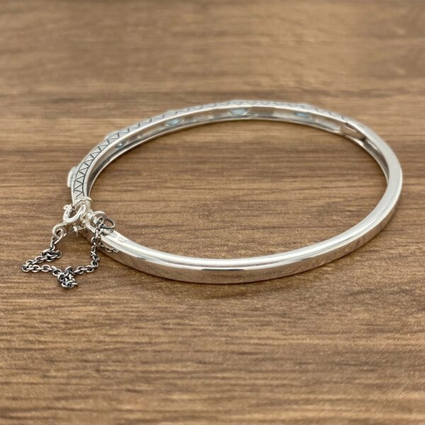 A silver bangle bracelet with turquoise stones.