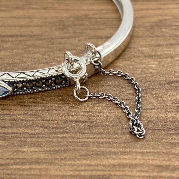 A silver bangle bracelet with turquoise stones.