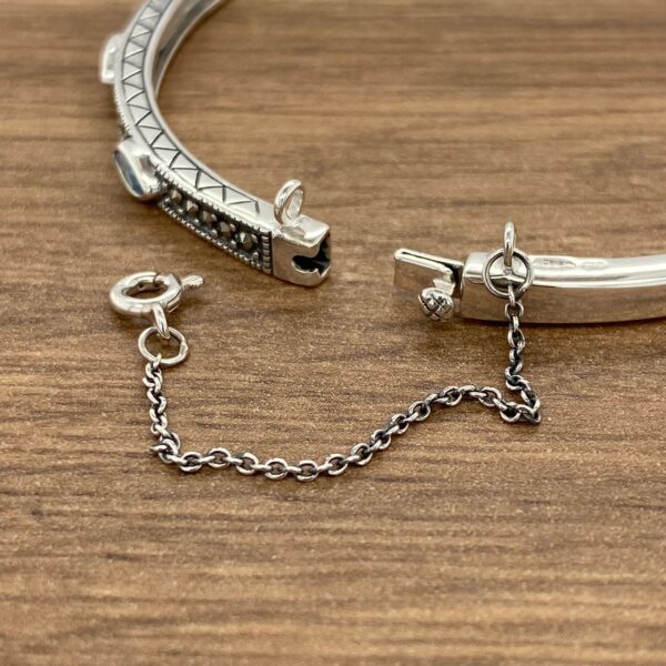 A silver bangle bracelet with turquoise stones.