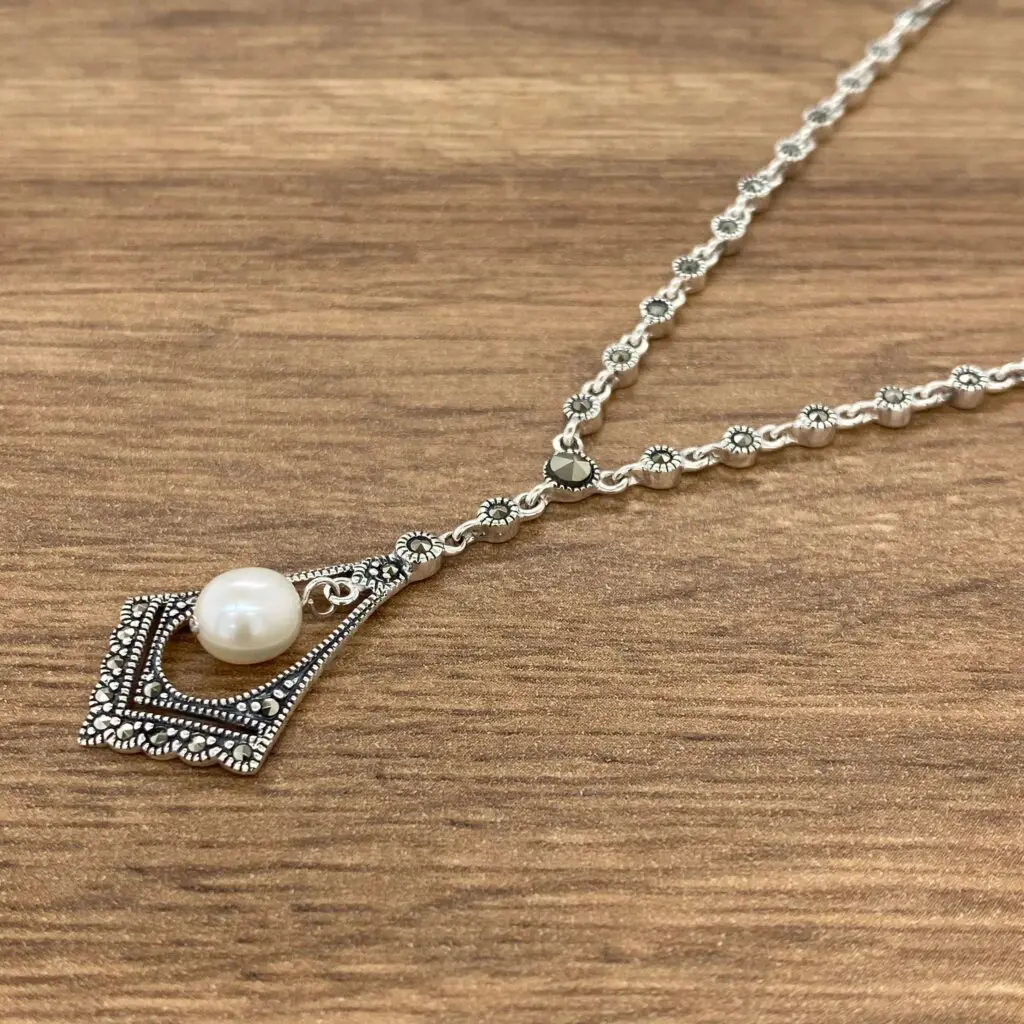 A silver necklace with a pearl on it.