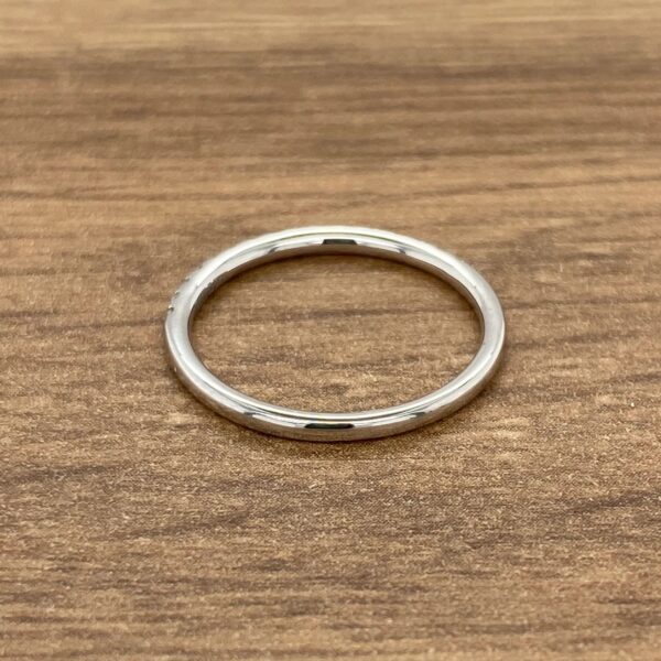 Silver wedding band on woodgrain background.