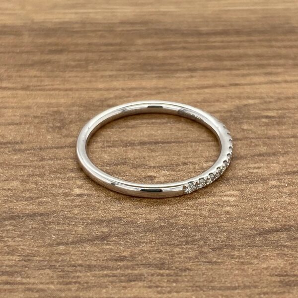 Thin diamond wedding band on wood.