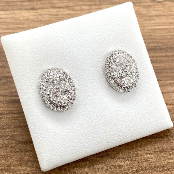 Diamond oval stud earrings on white display.