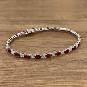 A ruby and diamond necklace on a wooden table.