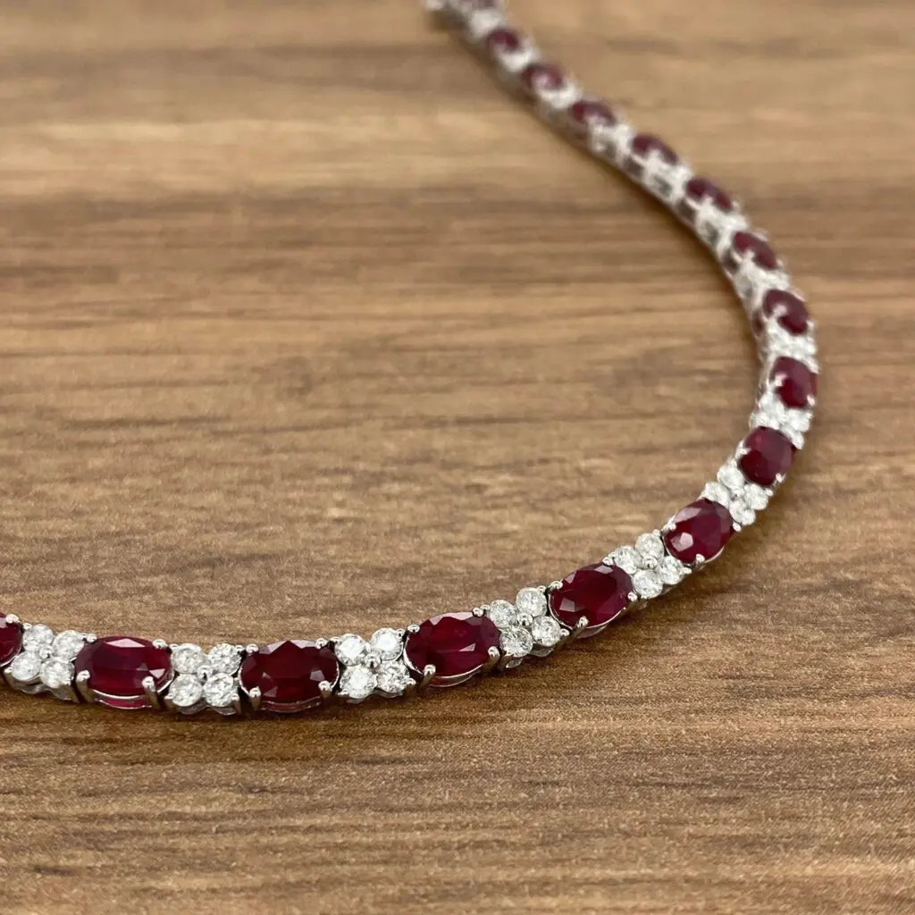A ruby and diamond necklace on a wooden table.