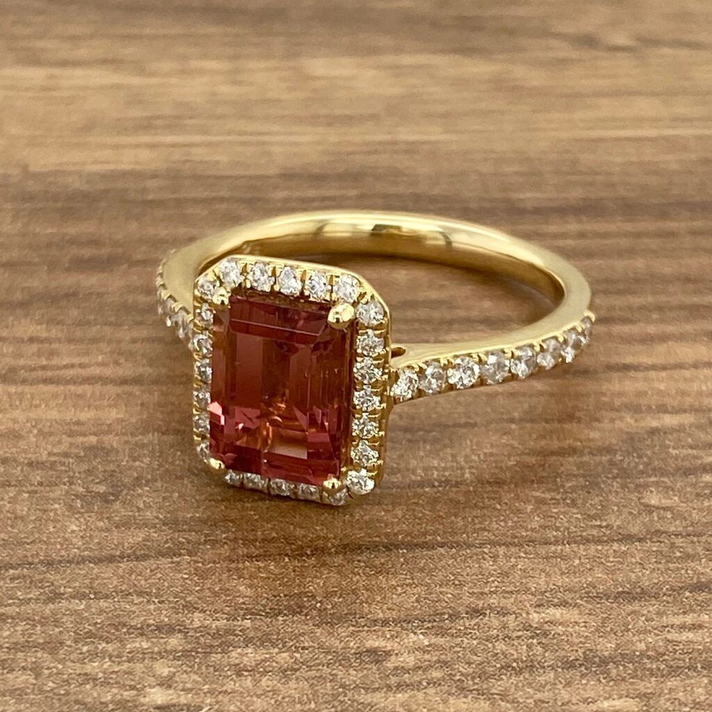 Gold ring with pink gemstone and diamonds.